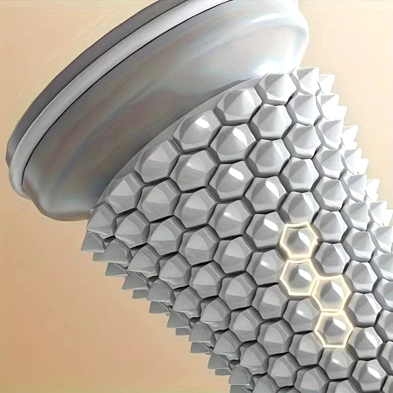 A close-up of a metallic silver cylindrical product with a textured honeycomb or faceted geometric pattern and a smooth curved top section, shown against a soft beige gradient background.